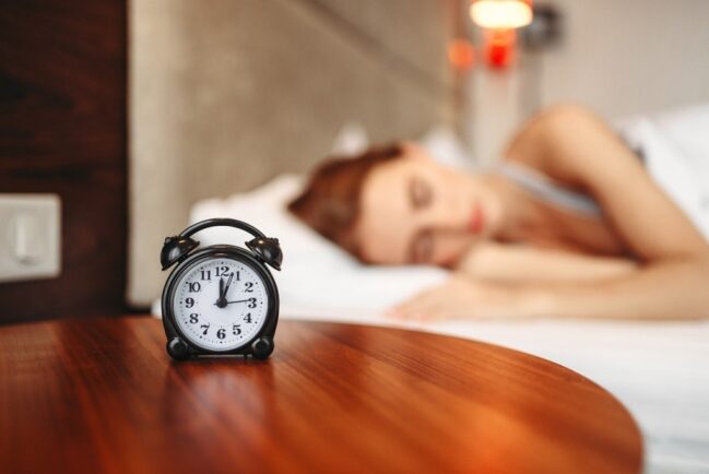 Girl sleeping next to alarm clock