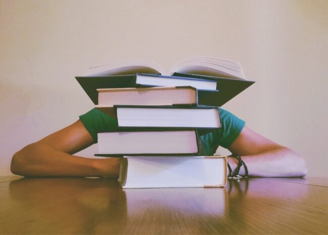 Man with a stack of books studying