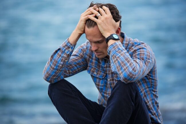 Man wearing blue shirt touching his hair